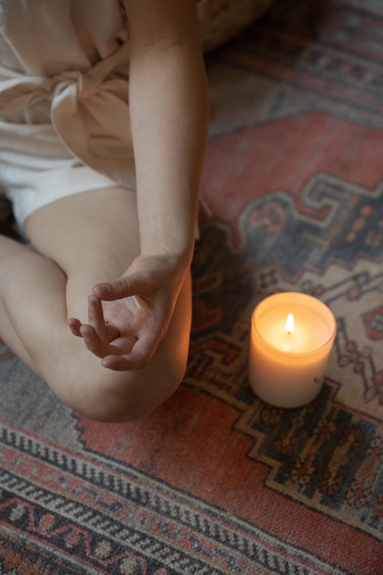 A seated figure meditating beside a lit candle